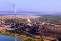 Metal processing facility in South Africa, with water in the foreground and the forst and sky in the background