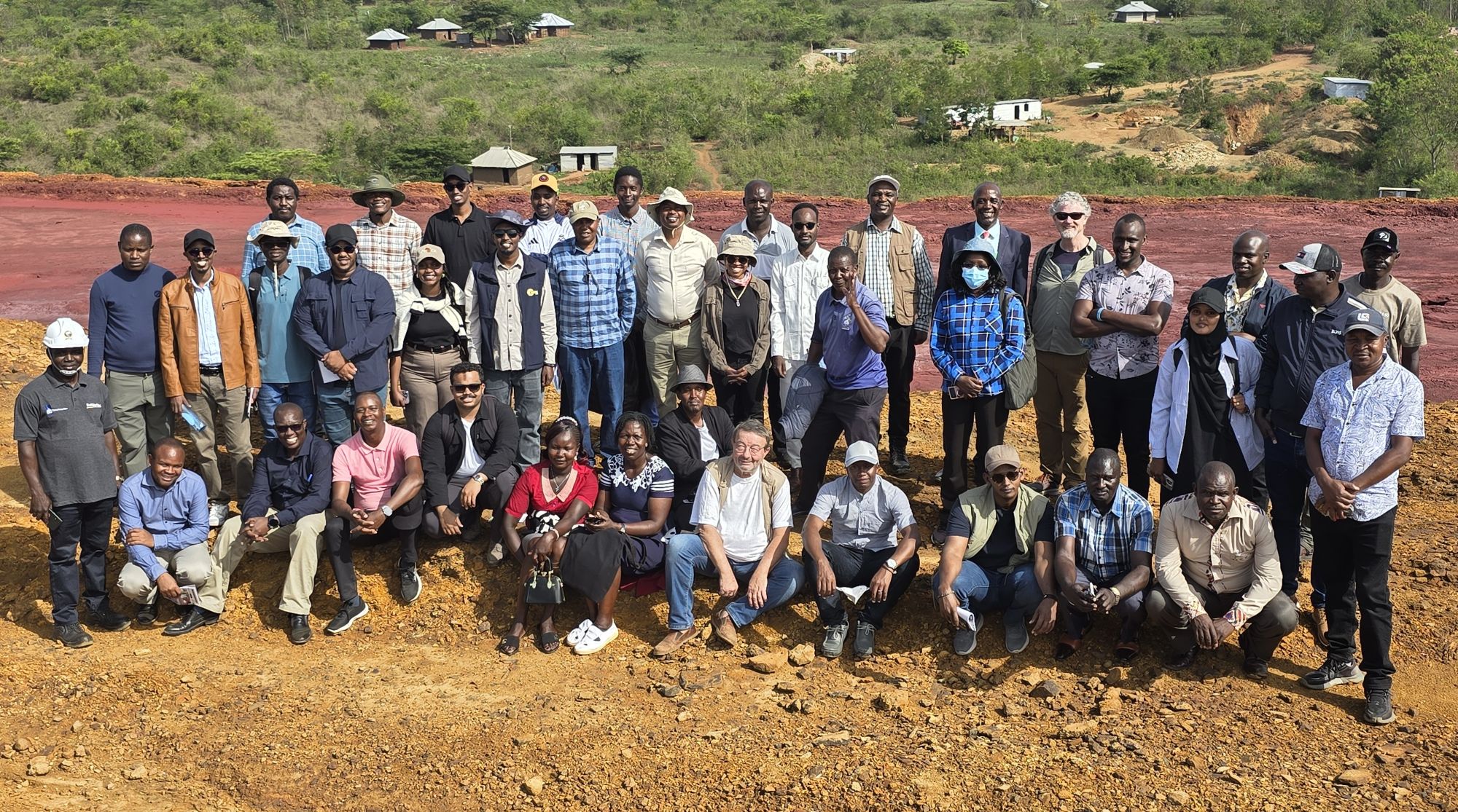 Group of people standing next to each other posing for a photo in a desert area.