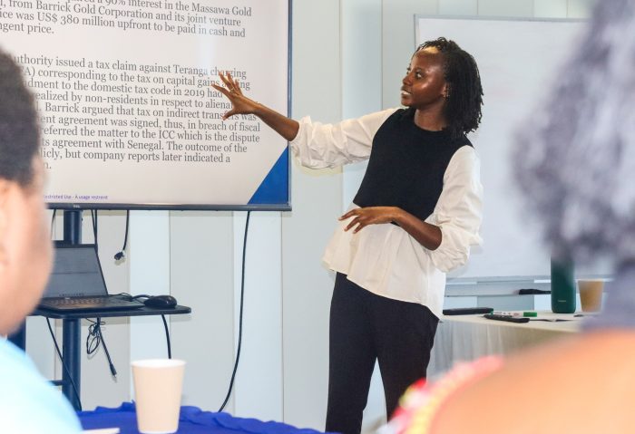 Tax expert Viola Tarus presents at a workshop on mining taxation in Papua New Guinea, standing in front of a screen