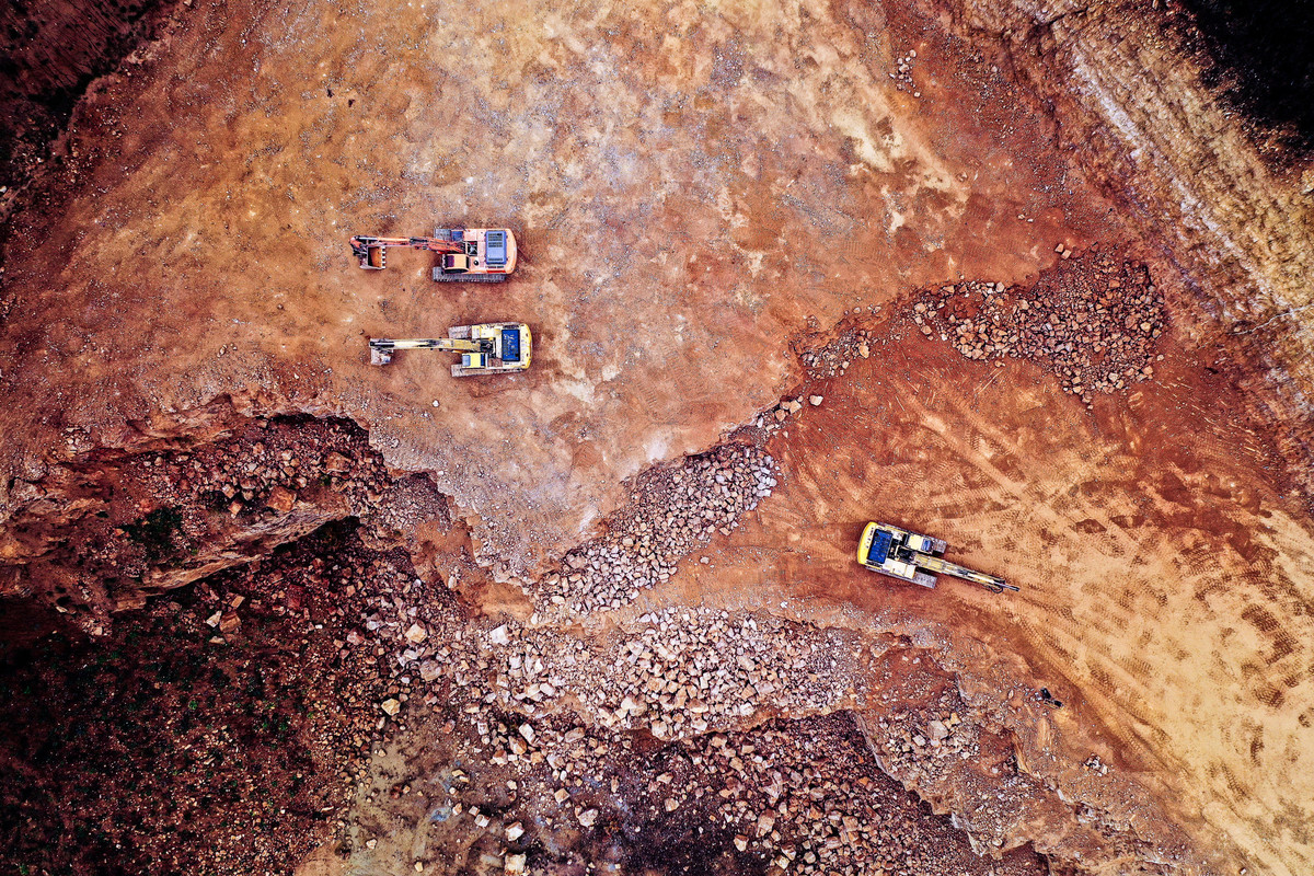 Aerial photo of diggers in a red quarry.