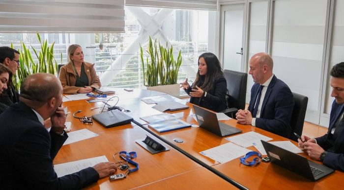 A meeting table and six persons discussing, with papers on the table. 